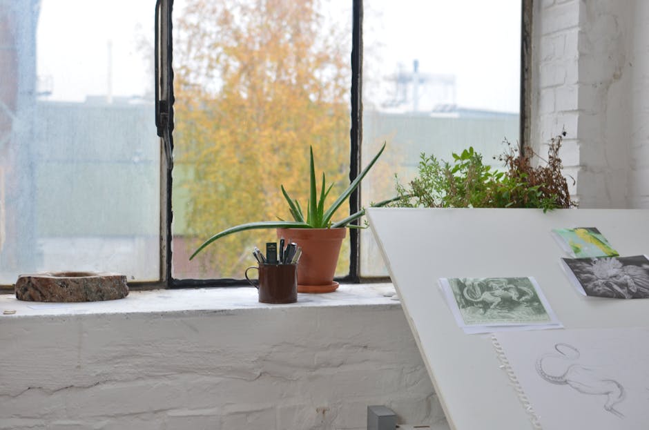 An artist's desk with traditional art supplies like fine liners, markers, and textured paper