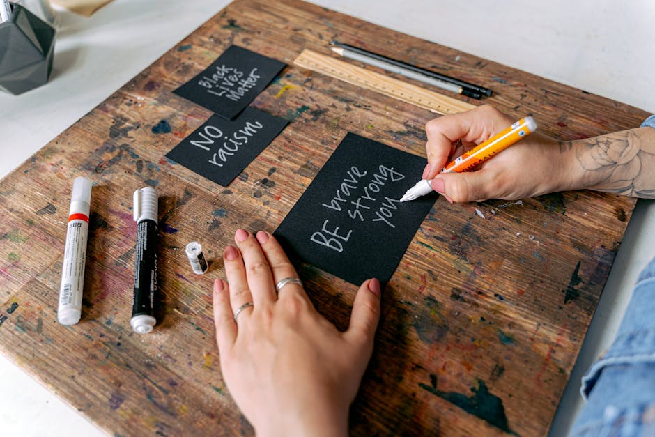 An artist working on a digital tablet, creating social justice-themed artwork surrounded by physical art materials