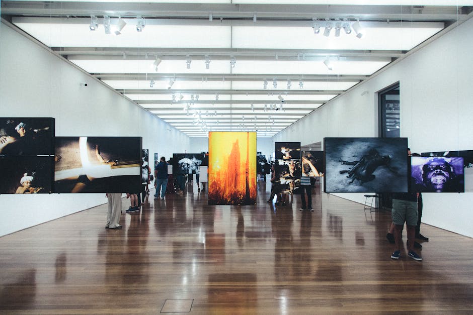 A diverse group of people viewing an art exhibition featuring works that blend traditional cultural elements with contemporary styles