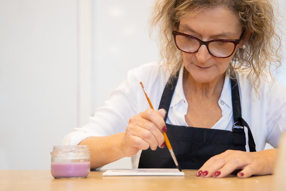 An elderly person deeply concentrating while working on a detailed painting