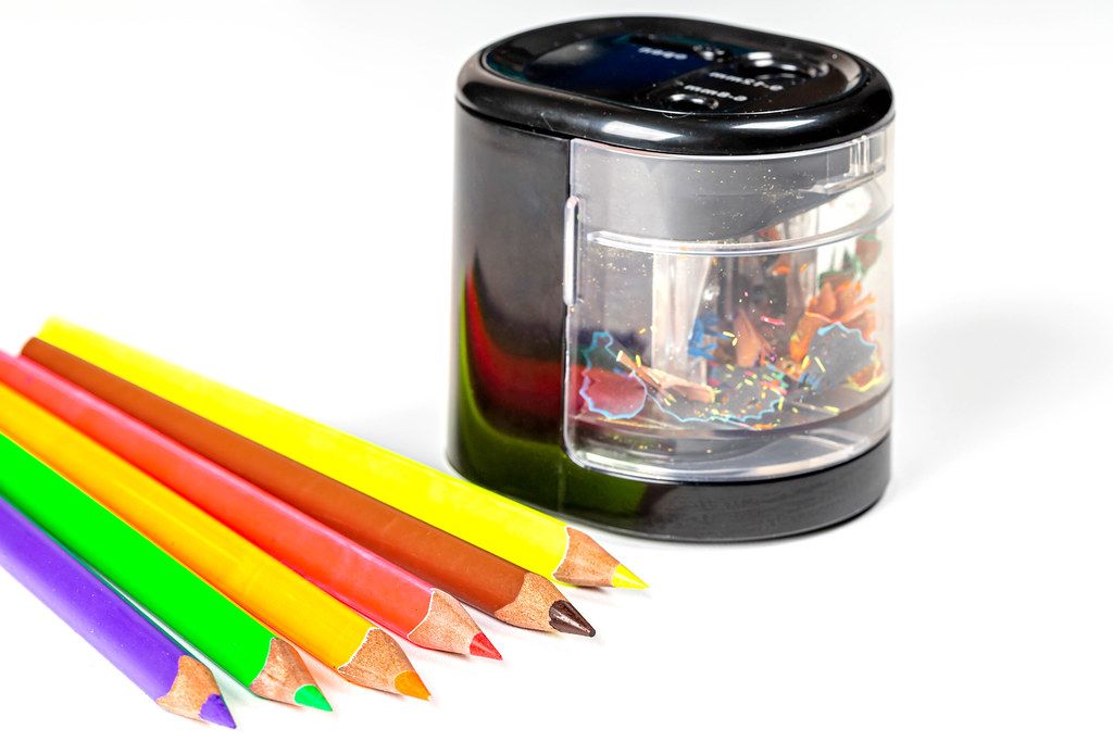 A group of pencil sharpeners, including manual handheld sharpeners and an electric sharpener, along with sharpened and unsharpened pencils.