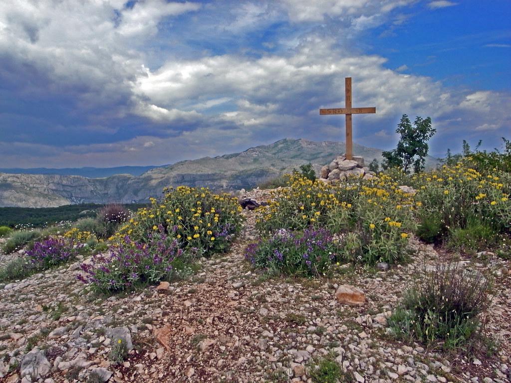 A small wooden cross on a hill overlooking a vast Andean landscape, symbolizing the themes in Church's Heart of the Andes